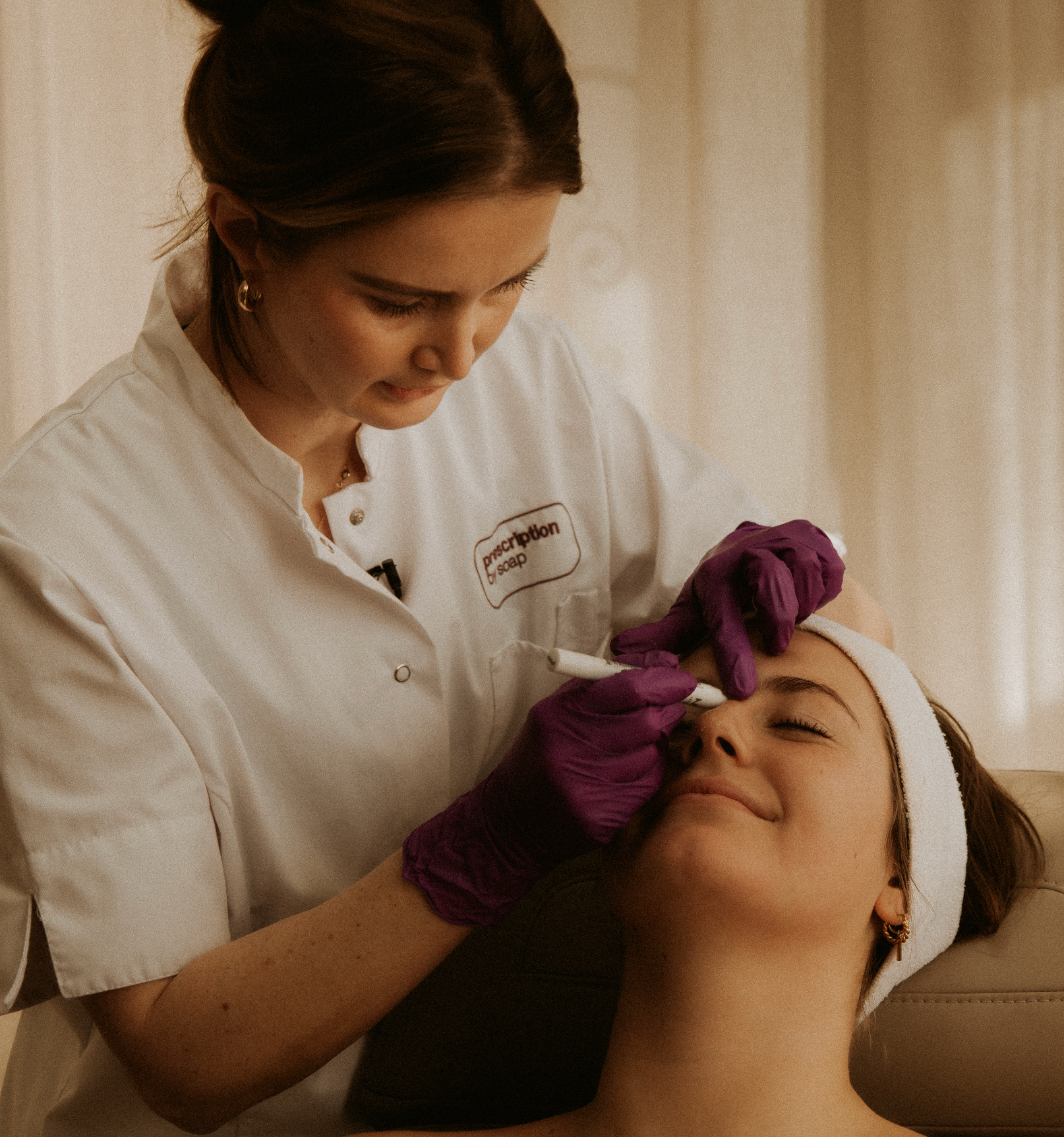 Er vindt een behandeling (Mesobo-Tox) plaats. Een skin expert behandeld een vrouw die op een behandel stoel ligt 
